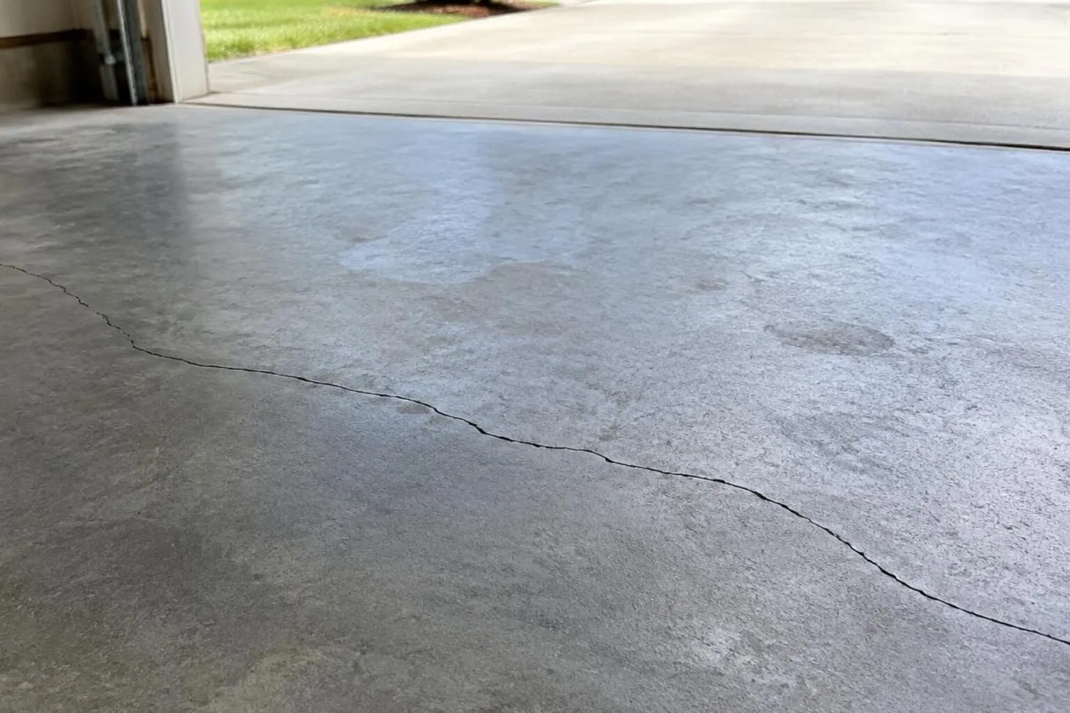 Garage concrete floor with a modest visible crack in daylight from an open door